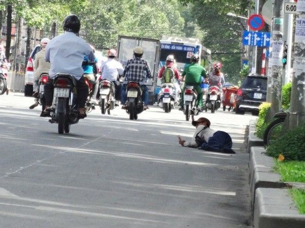 Người nằm bên đường, vừa bán vé số, vừa xin ăn - Ảnh: Mạnh Khang